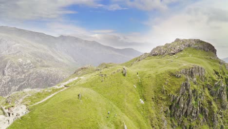 Stunning-aerial-reveal-of-Snowdonia-Nation-Park-over-Mount-Snowden-as-hikers-follow-the-trail-to-the-summit---Outdoors,-wilderness-and-nature-concepts---Welsh-natural-landscapes