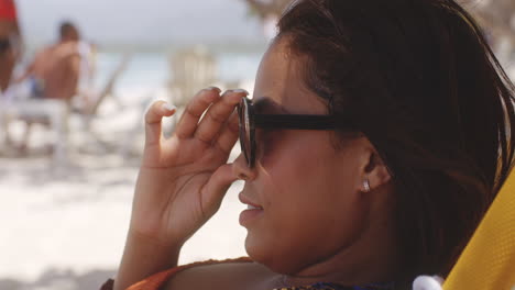 Latino-Mädchen-Posiert-Für-Einen-Lächelnden-Kopfschuss,-Der-Eine-Sonnenbrille-Abnimmt,-Die-Sich-Im-Karibischen-Strandresort-Entspannt