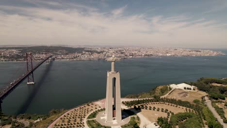 Drone-forward-moving-toward-Lisbon-city-capturing-the-statue-of-Cristo-Rei-and-Ponte-25-de-Abril