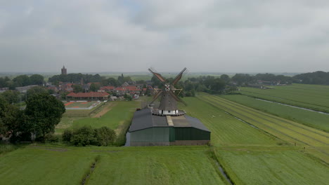 Jib-up-of-spinning-wind-mill-with-a-small-rural-town-in-the-background