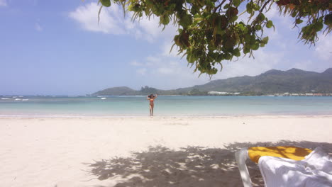 Wide-Scenic-View-of-Latino-Lady-Return-from-Swim-in-Sea-on-Tropical-Beach-Resort-Playa-Teco-Maimon,-gentle-zoom