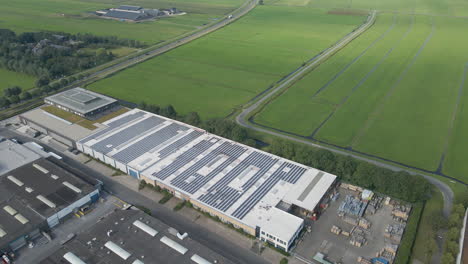 Cinematic-aerial-of-large-industrial-building-with-a-rooftop-filled-with-solar-panels