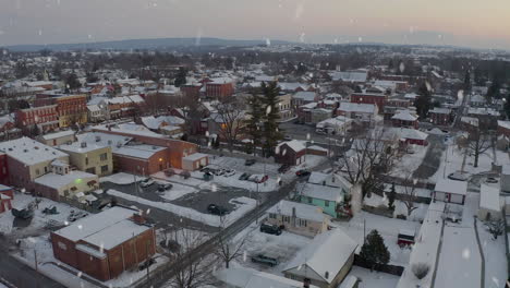 Aerial-establishing-shot-of-small-town-in-USA,-covered-in-snow-at-sunset,-sunrise