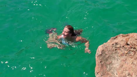 Blonde-girl-swimming-in-clear-blue-calm-water,-doing-the-breaststroke-and-concentrating-on-the-water,-She-is-on-holiday-in-the-south-of-Spain-and-enjoying-her-vacation-and-the-tranquility-it-brings