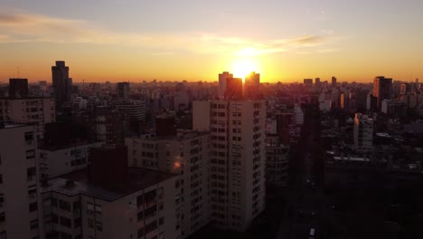 Silueta-De-Bloques-De-Apartamentos-De-Gran-Altura-En-Buenos-Aires-Durante-La-Puesta-De-Sol-Dorada,-4k---Vuelo-Aéreo-Ascendente-Hacia-El-Cielo-Iluminado