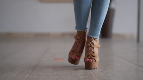 Close-up-of-woman's-feet-walking-towards-camera-in-high-heels-and-jeans-in-slow-motion