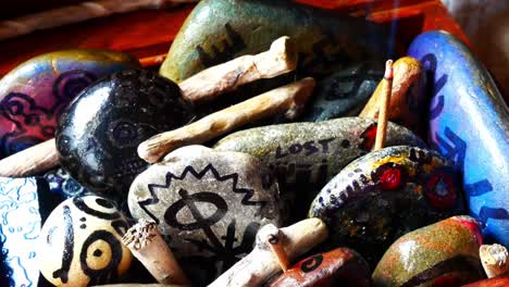 Magical-painted-Viking-drawing-patterned-spiritual-stones-colourful-art-collection-in-wooden-box-with-burning-incense