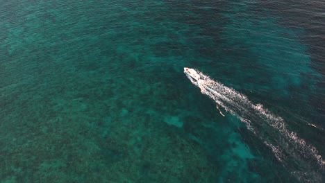 Weißes-Schnellboot-Segelt-Auf-Klarer-Türkisfarbener-Meeresoberfläche-Mit-Korallenriff-In-Richtung-Einer-Insel