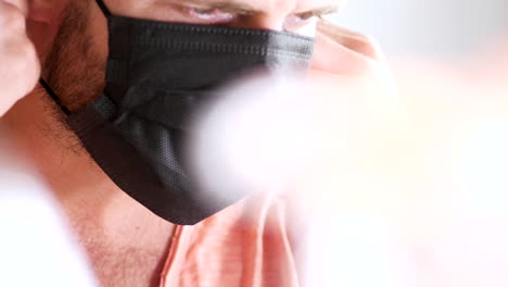 Bearded-man-removes-double-surgical-masks-from-face-to-breath-fresh-air,-bright-room
