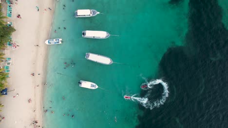 Weiße-Schnellboote-Auf-Klarer-Blauer-Meeresoberfläche-Mit-Korallen,-Die-An-Einer-Insel-Vorbeifahren