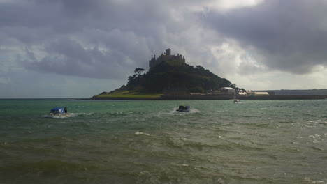 Small-Ferry-Boats-Sailing-On-The-Ocean-With-Saint-Michael's-Mount-In-Background---slow-motion