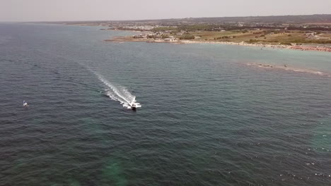 Speedboat-sails-along-Specchiolla-beach-coastline-in-Puglia,-Italy