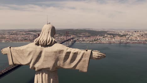 Panoramic-panning-shot,-sacred-statue-of-Christ-the-King-looking-at-Lisbon,-capital-city-of-Portugal