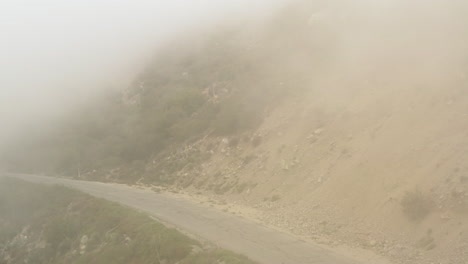 Drone-flying-backward-over-an-abandoned-asphalt-mountain-road