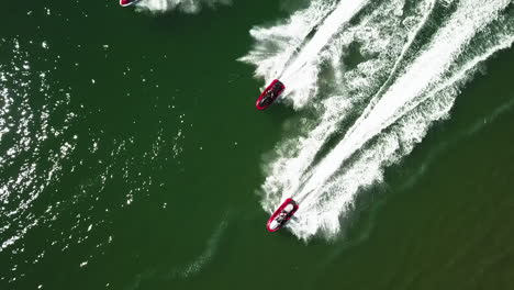 bird's-eye-view-of-a-group-of-red,-black-and-white-water-scooters-in-green-sea