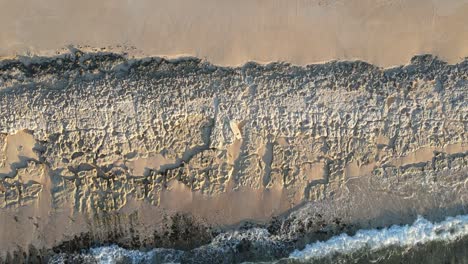 AERIAL---Waves-crashing-against-rocky-beach-in-Exmouth,-Australia,-top-down