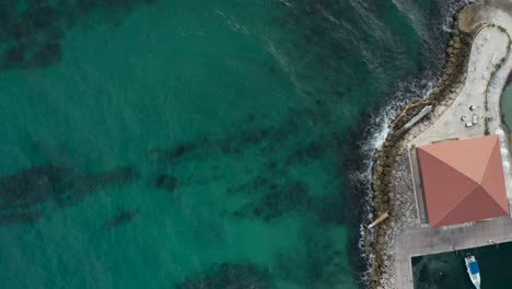 Aerial-drone-shot,-towards-the-outskirts-of-the-wave-breaker-and-the-lighthouse