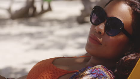 Close-up-of-Latin-Girls-Contented-Face-with-Sunglasses-Chilling-in-Shade-on-Beach