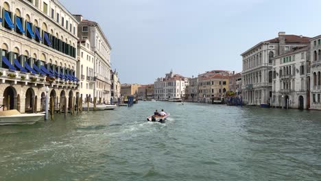 Two-Rich-Italian-Men-In-Private-Boat-Sailing-Between-Waterfront-Houses-In-Grand-Canal,-Venice,-Italy