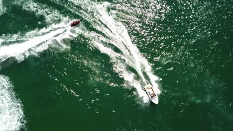 Aerial-bird's-eye-top-view-of-yacht-and-jet-skis-water-choreography