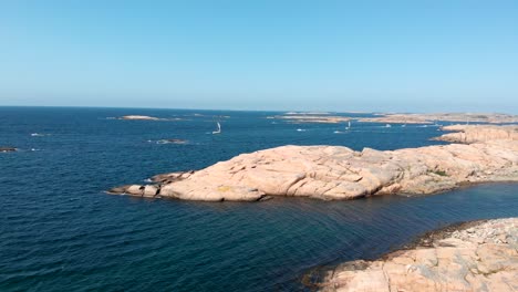Drone-Aerial-View,-Sailboats-by-Valon-Nature-Reserve-Coastline,-Sweden-on-Windy-Sunny-Summer-Day