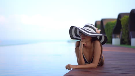 Edle-Exotische-Frau,-Die-In-Badeanzug,-Sonnenbrille-Und-Hut-Am-Schwimmbad-Liegt-Und-Ihren-Sommerurlaub-Genießt-Und-Entspannt,-Vollbild
