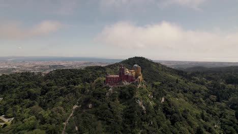 Pena-Palace-against-the-lush-forest-and-cloudy-sky,-Sintra-Natural-Park,-Portugal