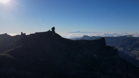 Fliegen-Durch-Die-Luft-Inmitten-Von-Baumwipfeln-In-Richtung-Des-Berühmten-Großen-Felsens,-Roque-Nublo,-In-Gran-Canaria-Bei-Einem-Wunderschönen-Blauen-Himmel