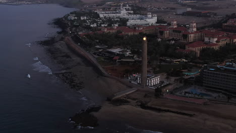 Aerial-shot-of-Maspalomas-Lighthouse-with-light-in-the-dusk