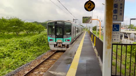 Panorámica-De-Izquierda-A-Derecha-Siguiendo-Un-Tren-Local-Que-Sale-De-Una-Estación-Rural-En-Japón