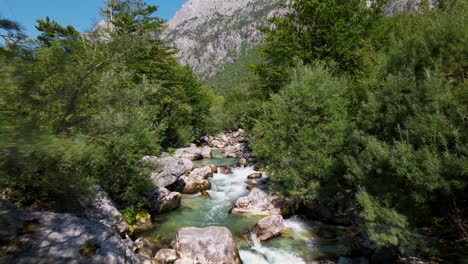 Cinematic-shot-of-alpine-river-with-clean-water-streaming-through-stones-and-trees-in-Valbona-valley,-Albania