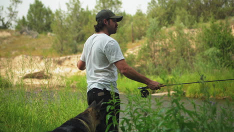 Caucasian-man-accompanied-by-his-German-Shepherd-dog-fly-fishing-in-river