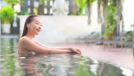 Pretty-Sexy-Exotic-Asian-Woman-in-Swimming-Pool-of-Spa-Center-Enjoying,-Relaxing-With-Smile,-Full-Frame-Slow-Motion