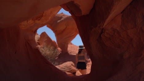 Junge-Frau-Zu-Fuß-Zwischen-Seltsamen-Natürlichen-Bögen,-Felsformation-Aus-Rotem-Sandstein-Im-Valley-Of-Fire-State-Park,-Nevada,-USA