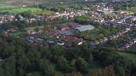 Lush-green-British-suburb-neighbourhood-alongside-M56-motorway-descending-aerial-shot