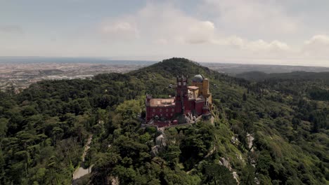 Aerial-orbiting-shot-around-Pena-palace,-the-famous-historic-attraction-on-Sintra-hills,-Portugal