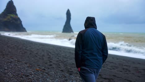 Back-View-Of-A-Male-Tourist-Walking-Alone-At-Reynifjara-Black-Sand-Beach-In-Vik,-Iceland