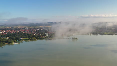 Wide-rotating-drone-shot-of-Keszthely-in-Hungary,-shooting-through-the-clouds