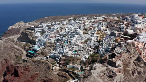 Panoramic-View-Of-Oia-Coastal-Town-On-The-Northwestern-Tip-Of-Santorini-In-Greece---aerial-drone-shot