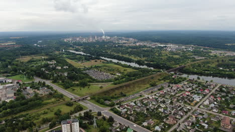 Cityscape-of-Jonava-and-chemical-industry-buildings-with-smoking-chimneys-in-horizon,-aerial-drone-view