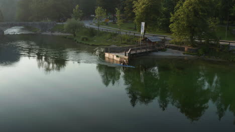 Man-Rowing-In-Canoe-Boat-On-Beautiful-Lake-Bohinj-In-Slovenia---aerial-drone-shot