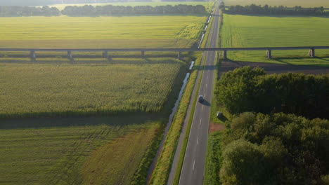 Carretera-Rural-Con-Un-Vehículo-Que-Viaja-Cerca-Del-Sitio-De-Prueba-Para-Trenes-Transrapid-Maglev-En-Lathen,-Alemania---Toma-Aérea-De-Drones