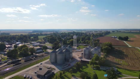 Drone-flying-towards-revealing-a-water-tower-and-many-silos-made-of-steel-in-a-farm-of-Trenton,-Kentucky