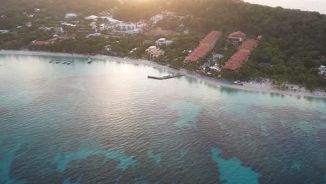 Barcos-Sobre-Las-Olas-En-Agua-De-Mar-Azul,-Palmeras-Y-Resorts-En-La-Costa-Caribeña