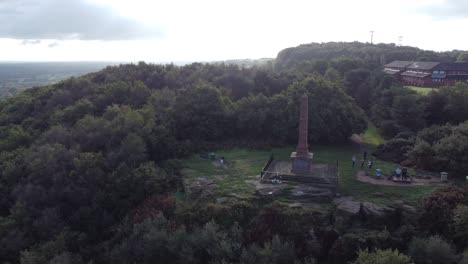 Aerial-view-sandstone-obelisk-war-memorial-Frodsham-hill-overlooking-Cheshire-Liverpool-skyline-pan-right