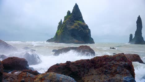 Weiße-Wellen,-Die-Gegen-Die-Felsen-Des-Schwarzen-Sandstrandes-In-Island-Spritzen