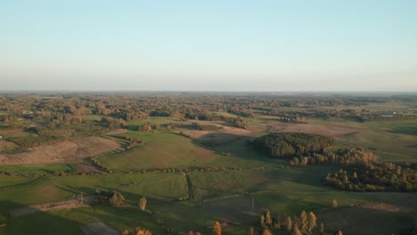 AERIAL:-Vast-Green-Fields-and-Forest-with-Golden-Blue-Sky-Over-Horizon