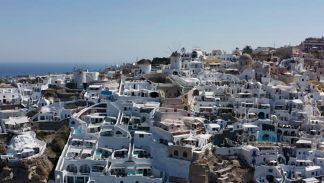 Coastal-Town-Of-Oia-On-The-Northwestern-Tip-Of-Santorini,-A-Greek-Aegean-Island---aerial-drone-shot