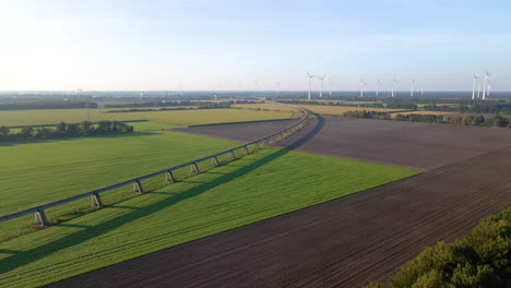 Luftaufnahme-über-Grüne-Felder,-Magnetische-Transrapid-Teststrecke-Und-Windmühlen-In-Der-Stadt-Lathen-In-Deutschland---Drohnenaufnahme