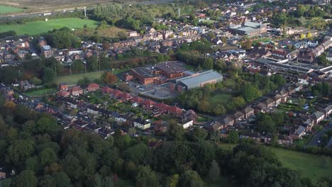 Lush-green-British-suburb-neighbourhood-alongside-M56-motorway-aerial-pull-back-descend